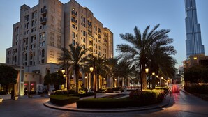 Een modern hotel met een centraal gelegen binnenplaats, palmbomen en uitzicht op de Burj Khalifa.