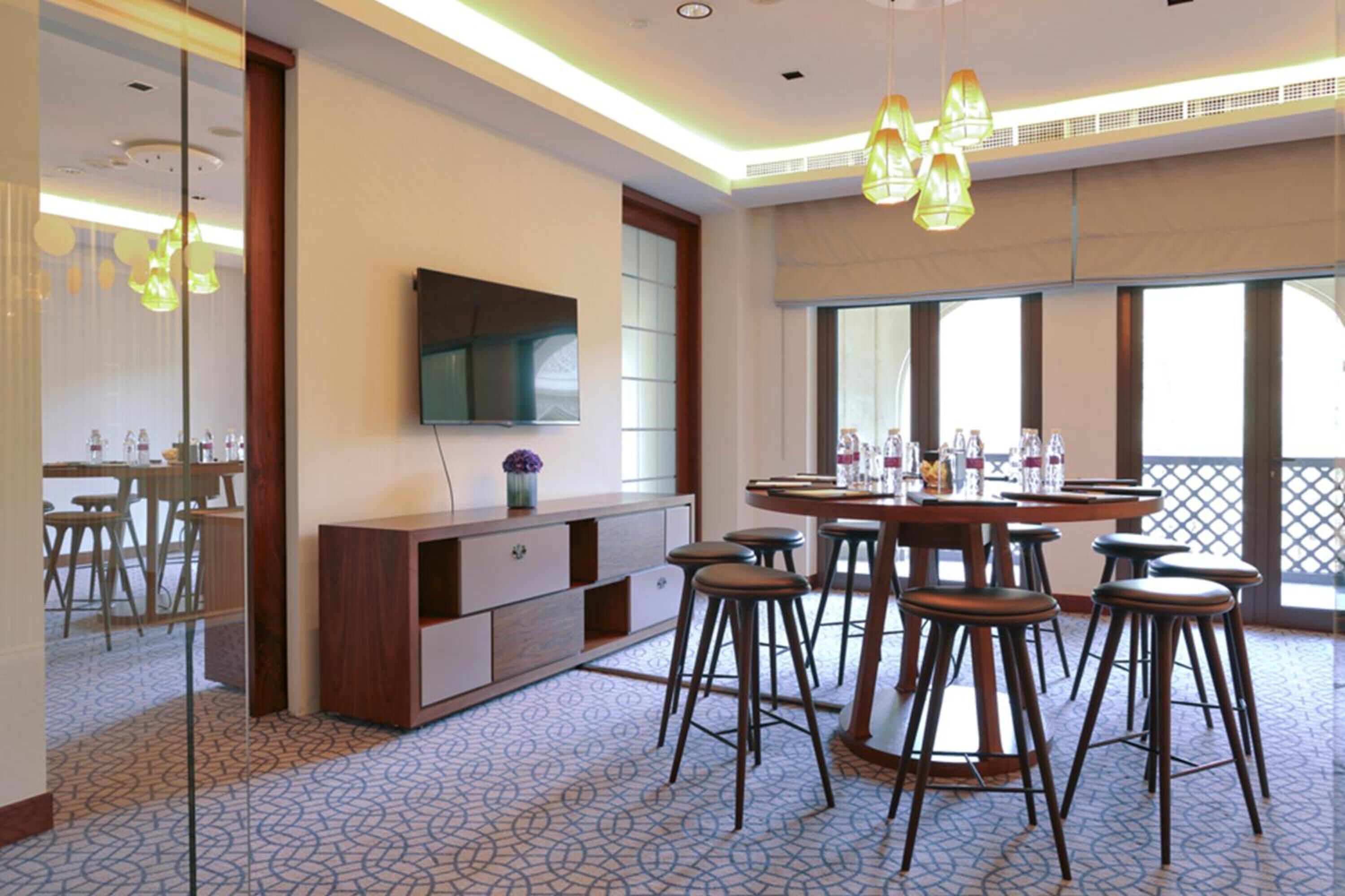 Un comedor moderno con una mesa redonda, taburetes de bar y un televisor en la pared.