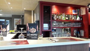 A bar area with a menu sign, glasses, and bottles. - Campanile Montluçon - St Victor (Saint-Victor)