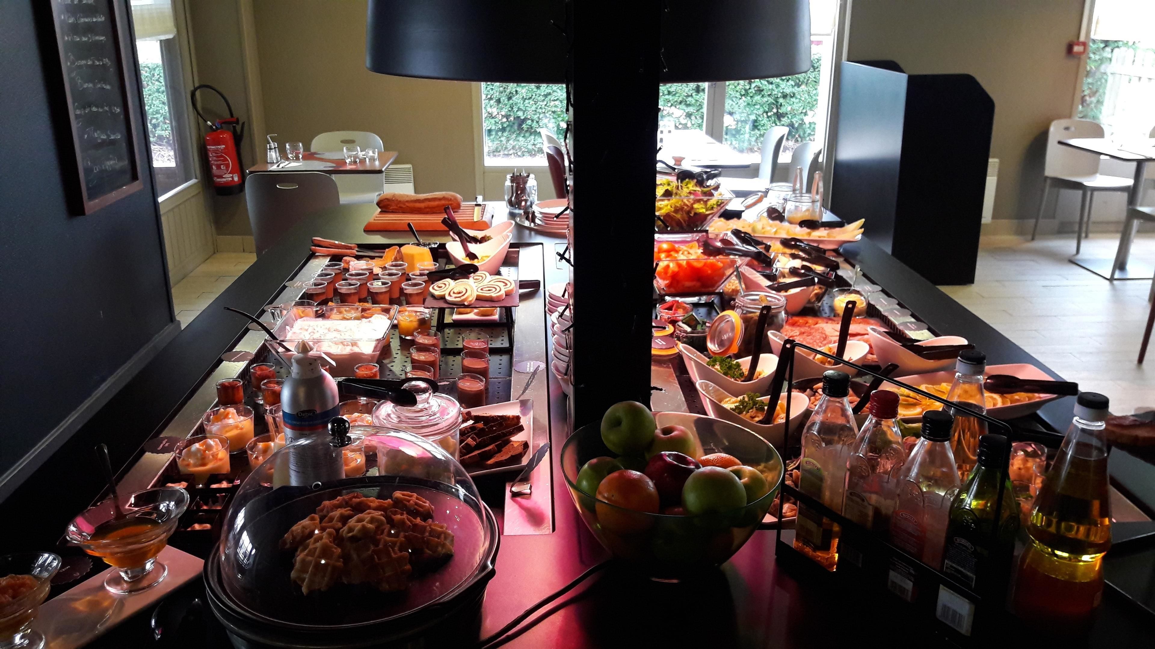 Un bufé con diversas opciones de comida, como waffles, frutas y bebidas.
