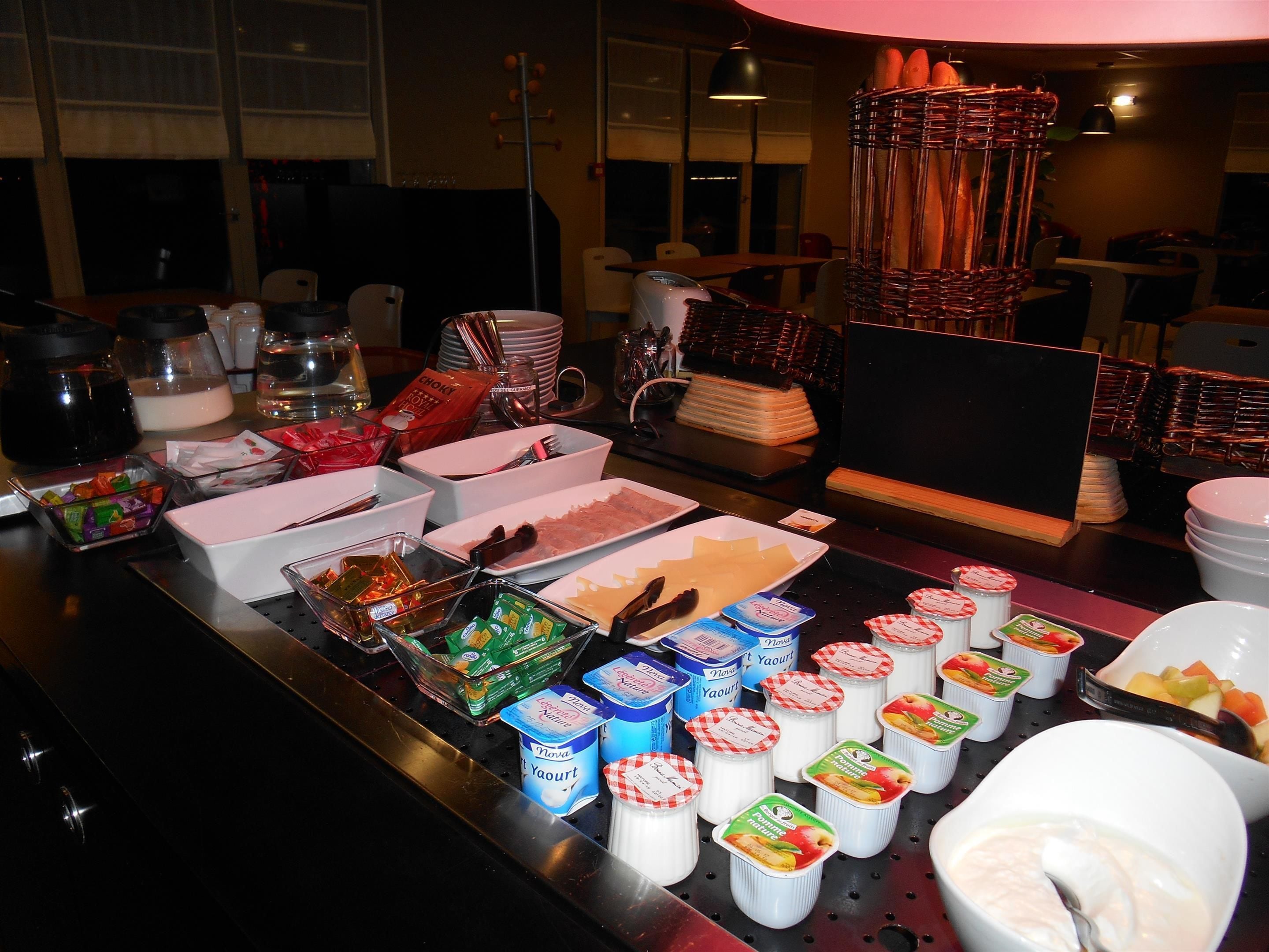A buffet setup with various food items and containers, including bowls of fruit, trays of cheese, and containers of yogurt.