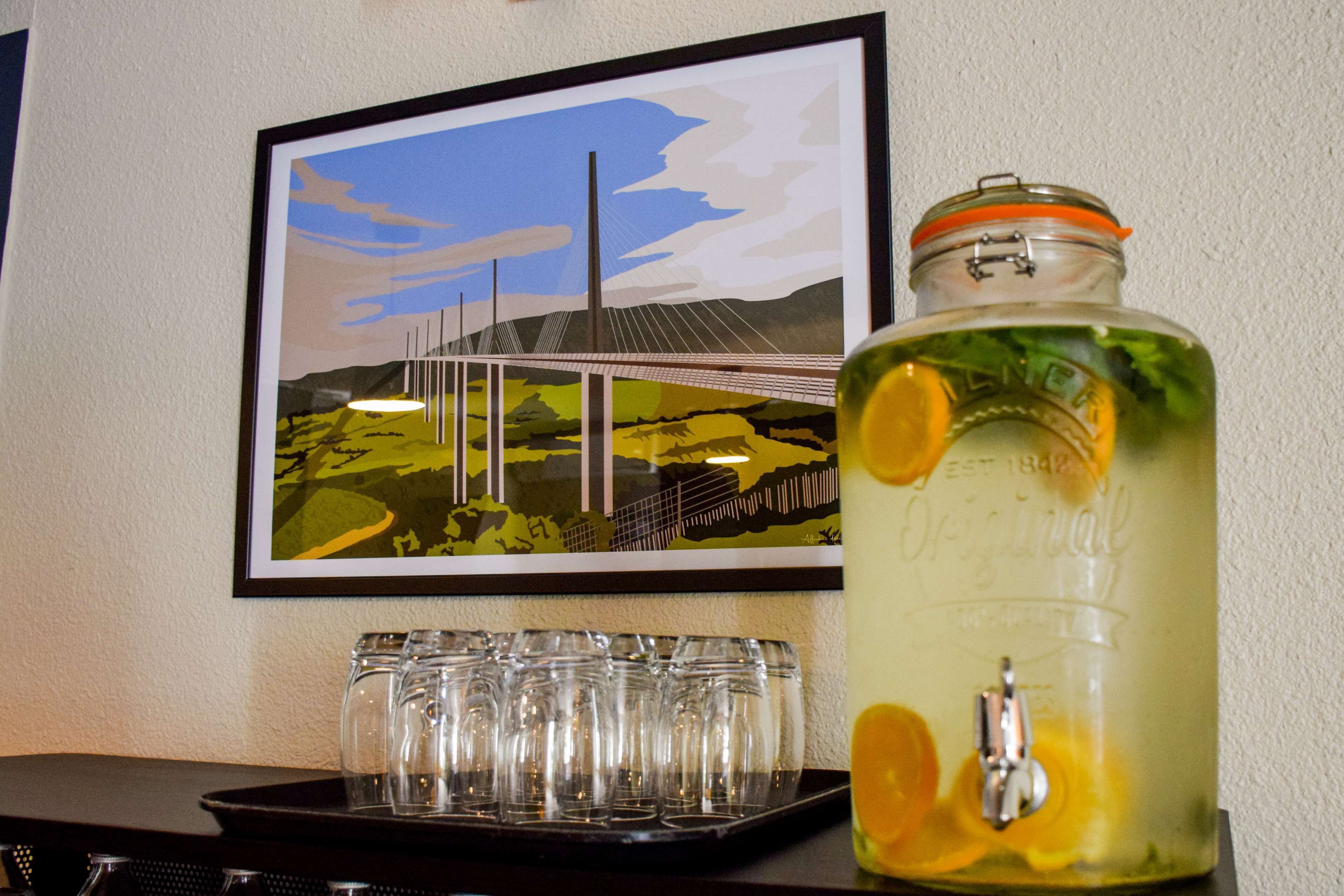 A jar of lemonade with a metal lid and a picture of a bridge in the background.