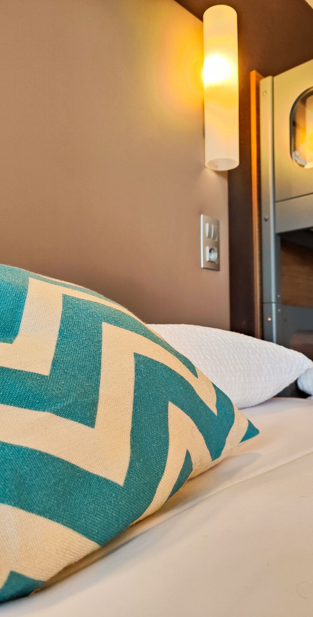 Habitación de hotel con cama, luz en la pared y ventana.