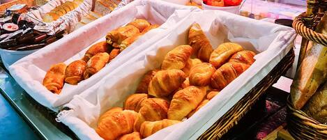 A display of assorted baked goods, including croissants and bread, in a bakery setting.