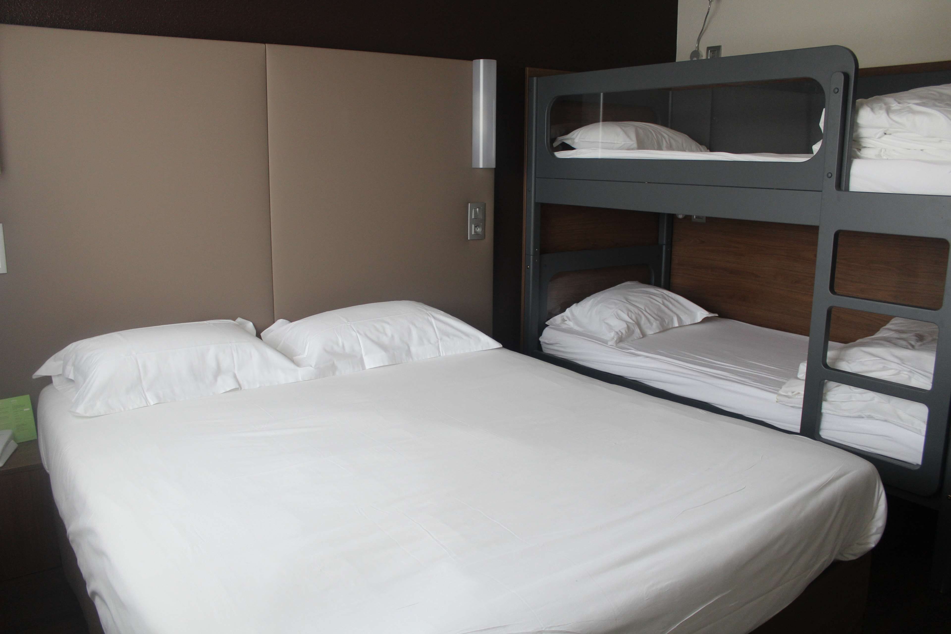 A bunk bed with a lower bunk and a single bed, both with white bedding.