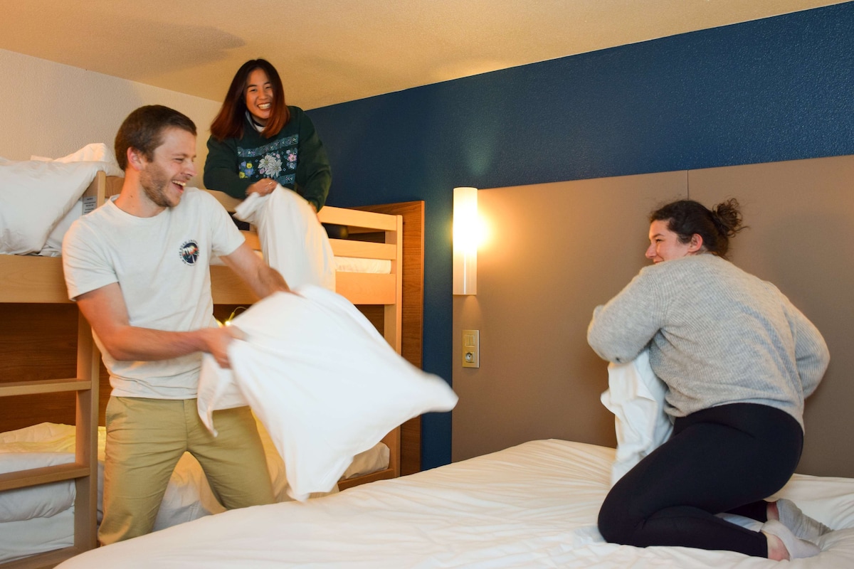 A room with bunk beds, a bedside lamp, and a wall-mounted light fixture.