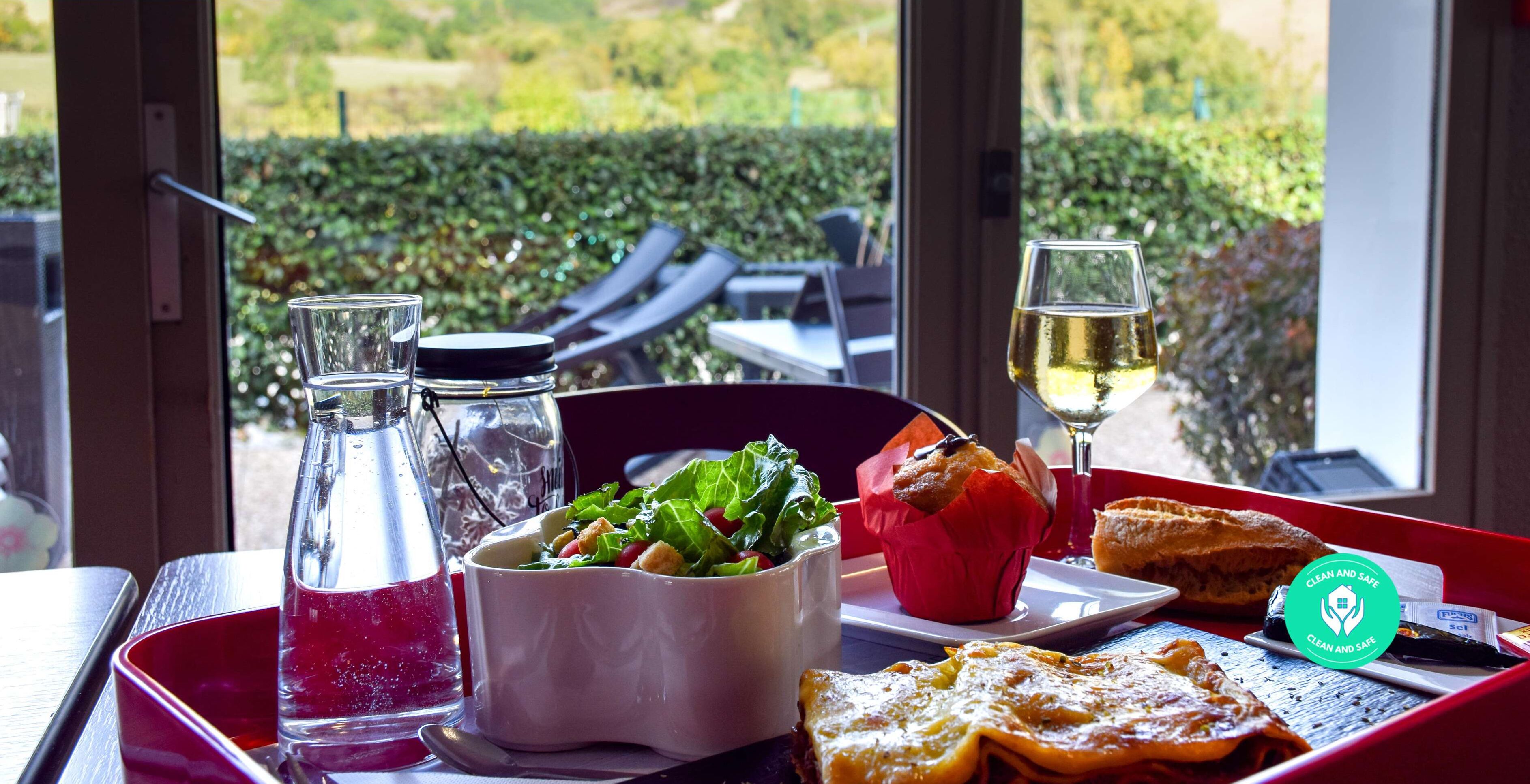 Une table à manger avec une salade, un muffin, du pain et un verre de vin blanc.