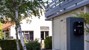 A reception area with a mailbox, a building entrance, and a pathway leading to a hotel.