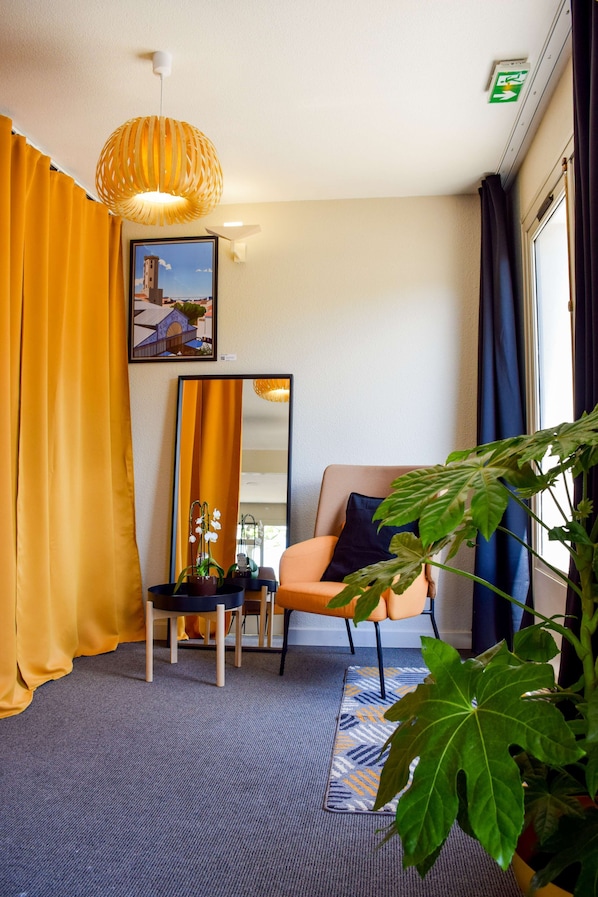Une pièce avec un grand miroir, un canapé, un fauteuil et une plante en pot.