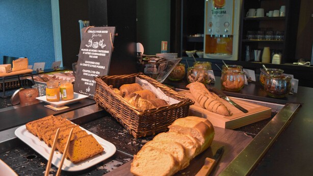 A breakfast buffet with various breads, pastries, and condiments.