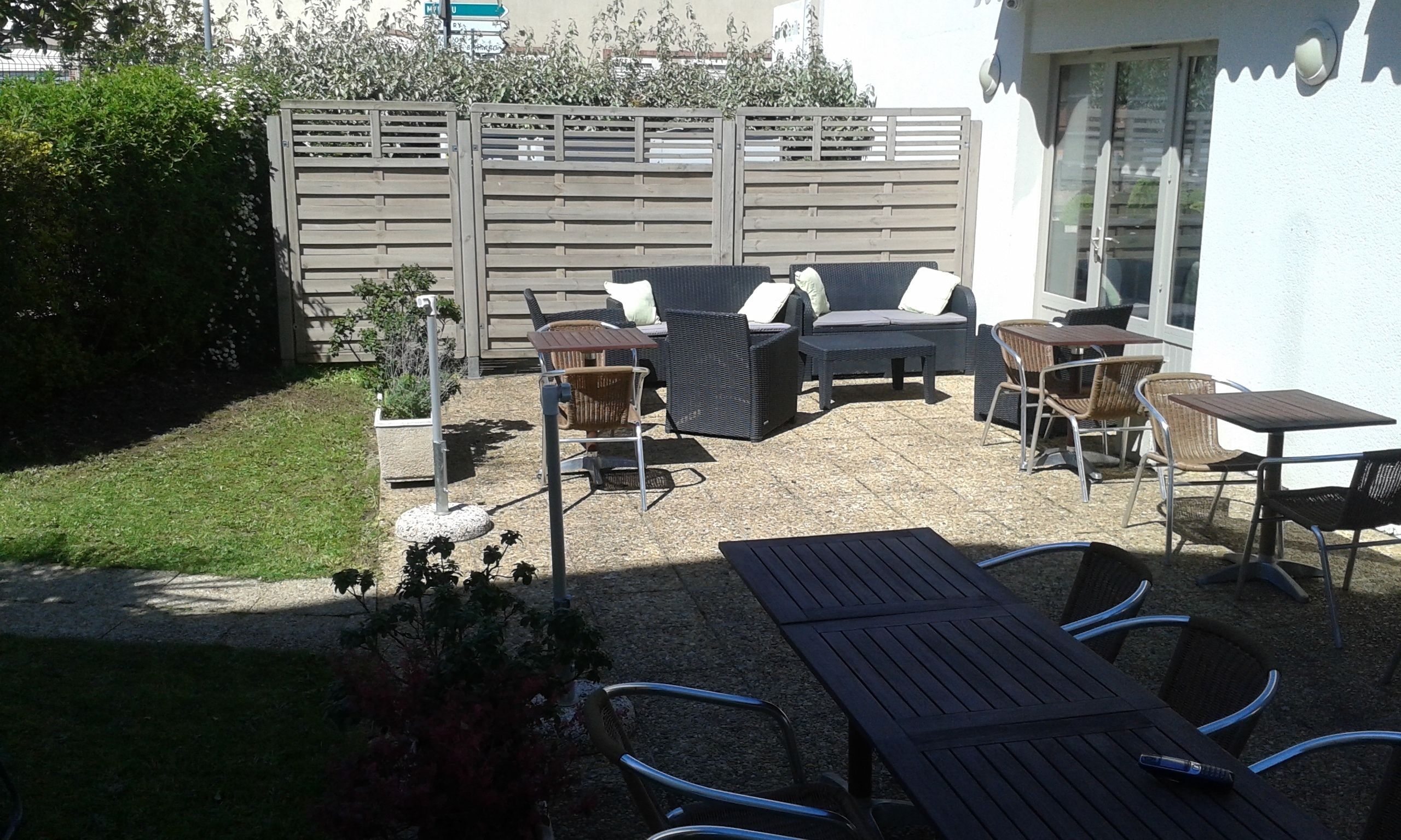 An outdoor patio with a seating area, including a sofa, chairs, and tables.