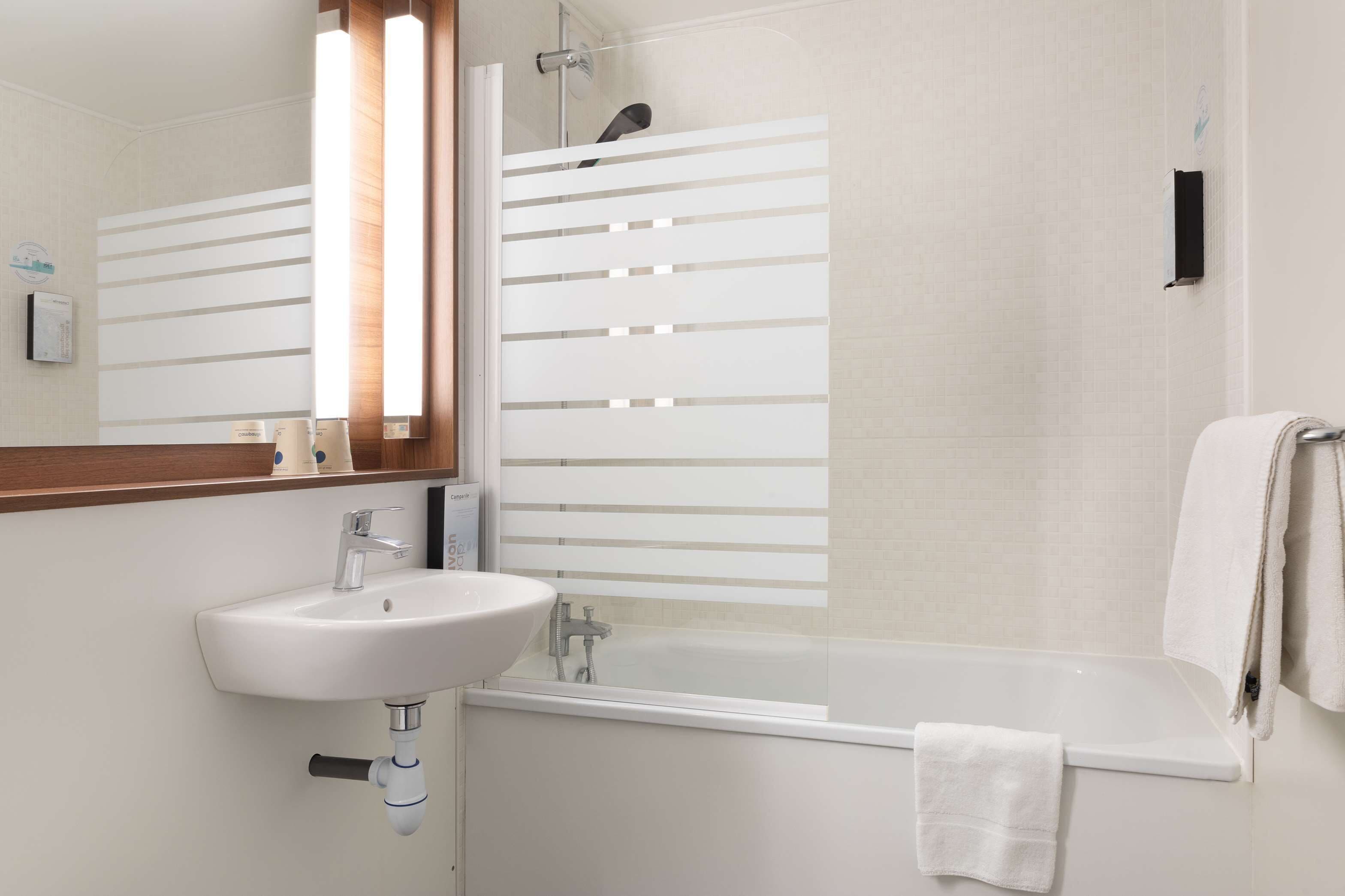Une salle de bain moderne avec un lavabo blanc, un miroir, une douche avec une porte en verre et une baignoire.