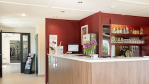 A reception area with a wooden counter, a computer, and a glass display case with bottles. - Campanile Dole (Dole)