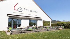 A restaurant with outdoor seating and a clear view of the surrounding landscape. - Campanile Dole (Dole)