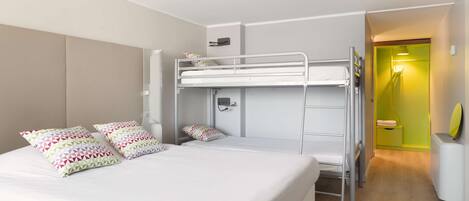 Habitación con literas, una cama blanca, dos almohadas, una mesita de noche y una pequeña mesita auxiliar.