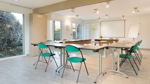 A modern conference room with a large table, green chairs, and a whiteboard. - Campanile Dole (Dole)