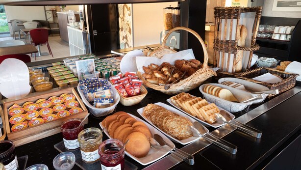 A buffet with various food items including pastries, bread, and condiments. - Campanile Dole (Dole)
