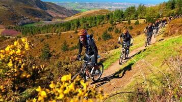 A group of cyclists on a mountain trail with a scenic view of hills and a distant town.