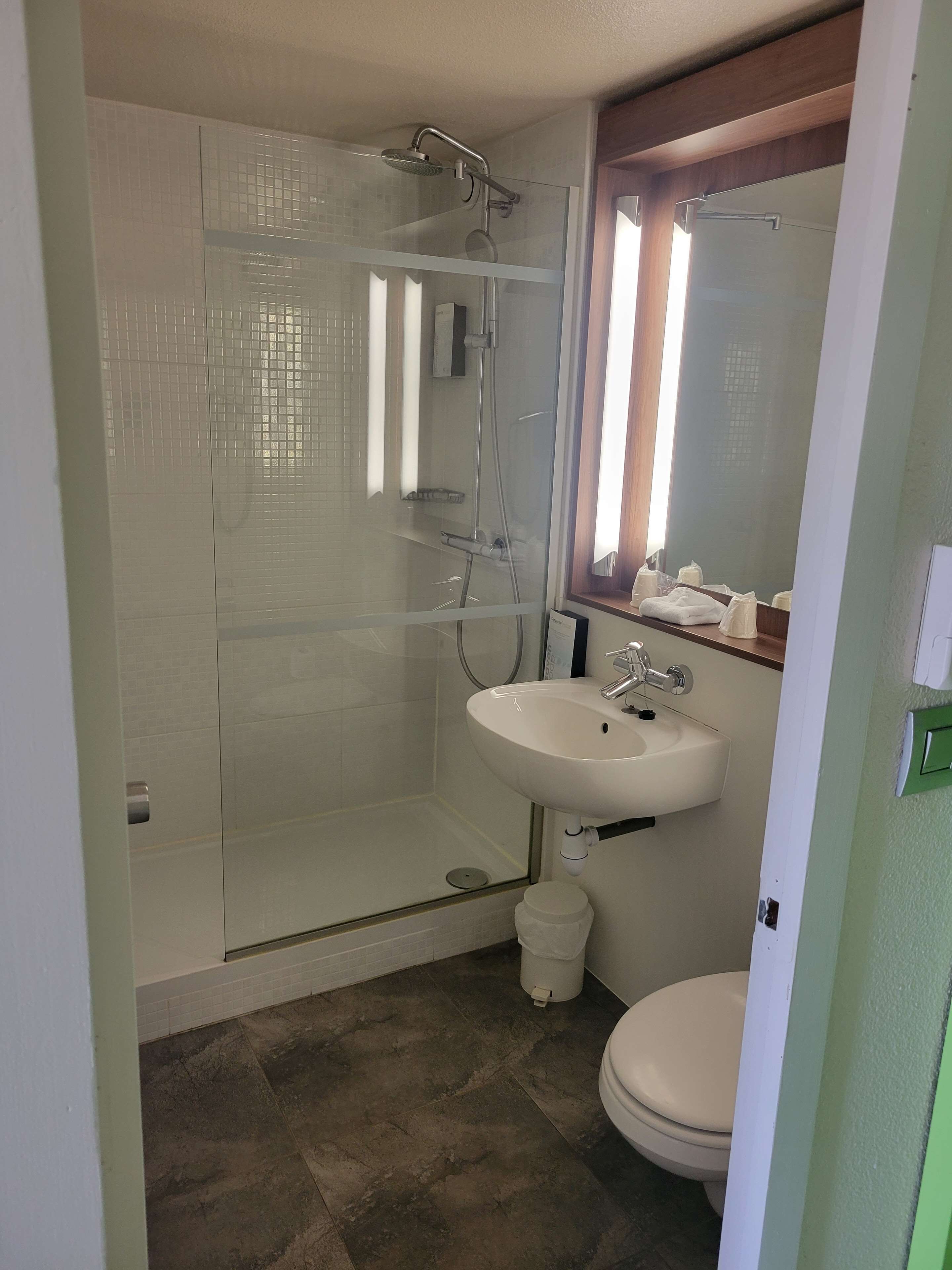 A bathroom with a glass-enclosed shower, a white sink, and a toilet.