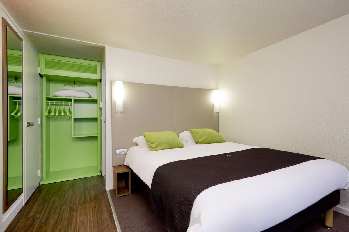 A hotel room with a bed, a green closet, and a nightstand.