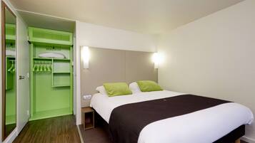 Una habitación de hotel con una cama, un armario verde y una mesita de noche.