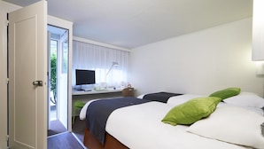 Une chambre d’hôtel avec deux lits, un bureau avec un ordinateur et une télévision.