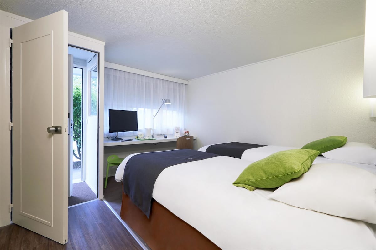 A hotel room with two beds, a desk with a computer, and a TV.