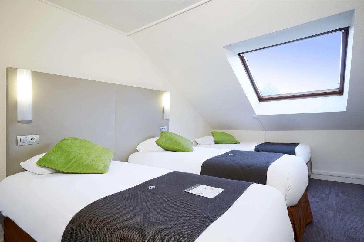 A hotel room with two beds, a skylight, and a small window.