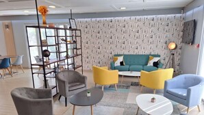 Una sala de estar moderna con un sofá color turquesa, sillas amarillas y grises, una mesa de centro y una estantería.