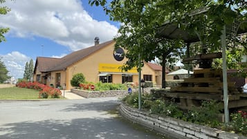 A restaurant with a yellow sign, a stone wall, and a covered outdoor seating area.