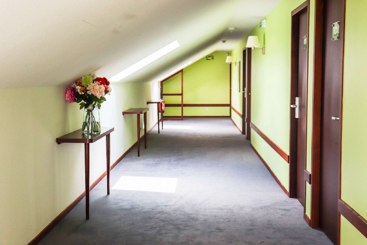 A hallway with a skylight, a vase of flowers on a table, and doors on the right.
