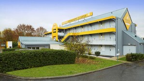 Een hotel met een modern design, gekenmerkt door een opvallend geel-grijs kleurenschema, meerdere verdiepingen en een centrale trap.