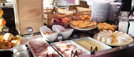 A buffet with various food items including fruits, meats, and cheeses.