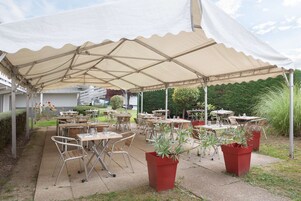 Un área de patio al aire libre con mesas y sillas bajo un toldo grande.