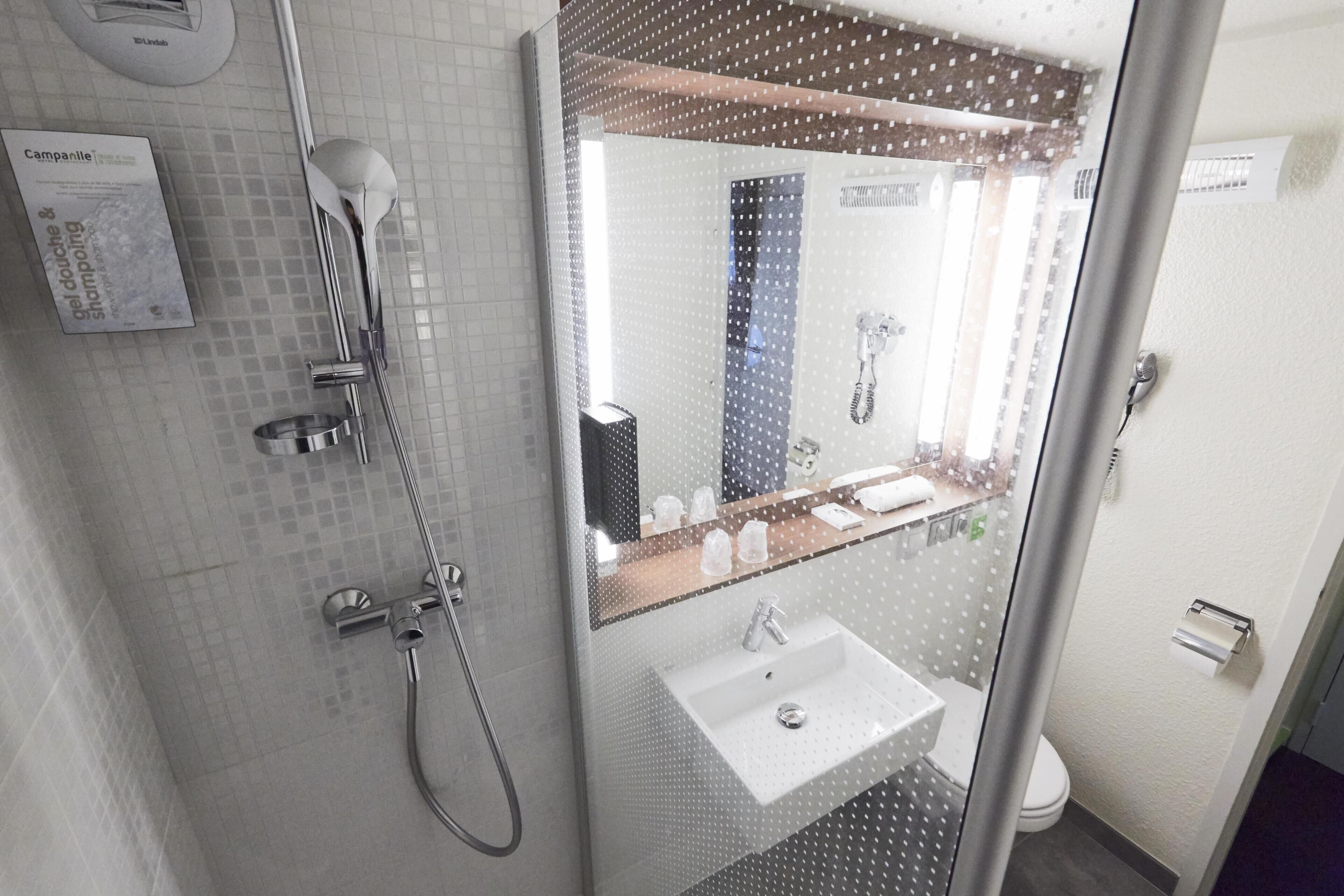 A modern bathroom with a shower, a sink, and a mirror.