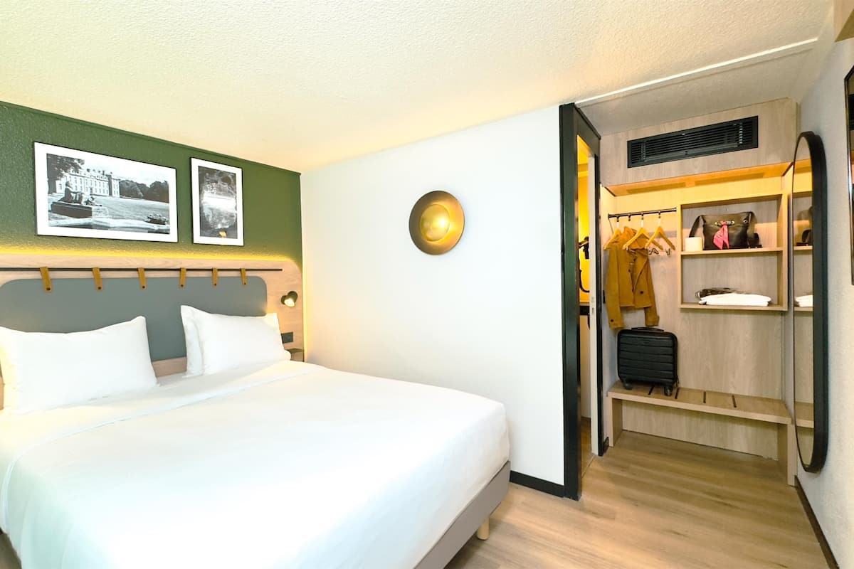 Ein Hotelzimmer mit einem Bett, einem Kleiderschrank und einem Spiegel.