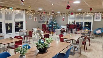 A restaurant with tables and chairs, a Christmas tree, and festive decorations.