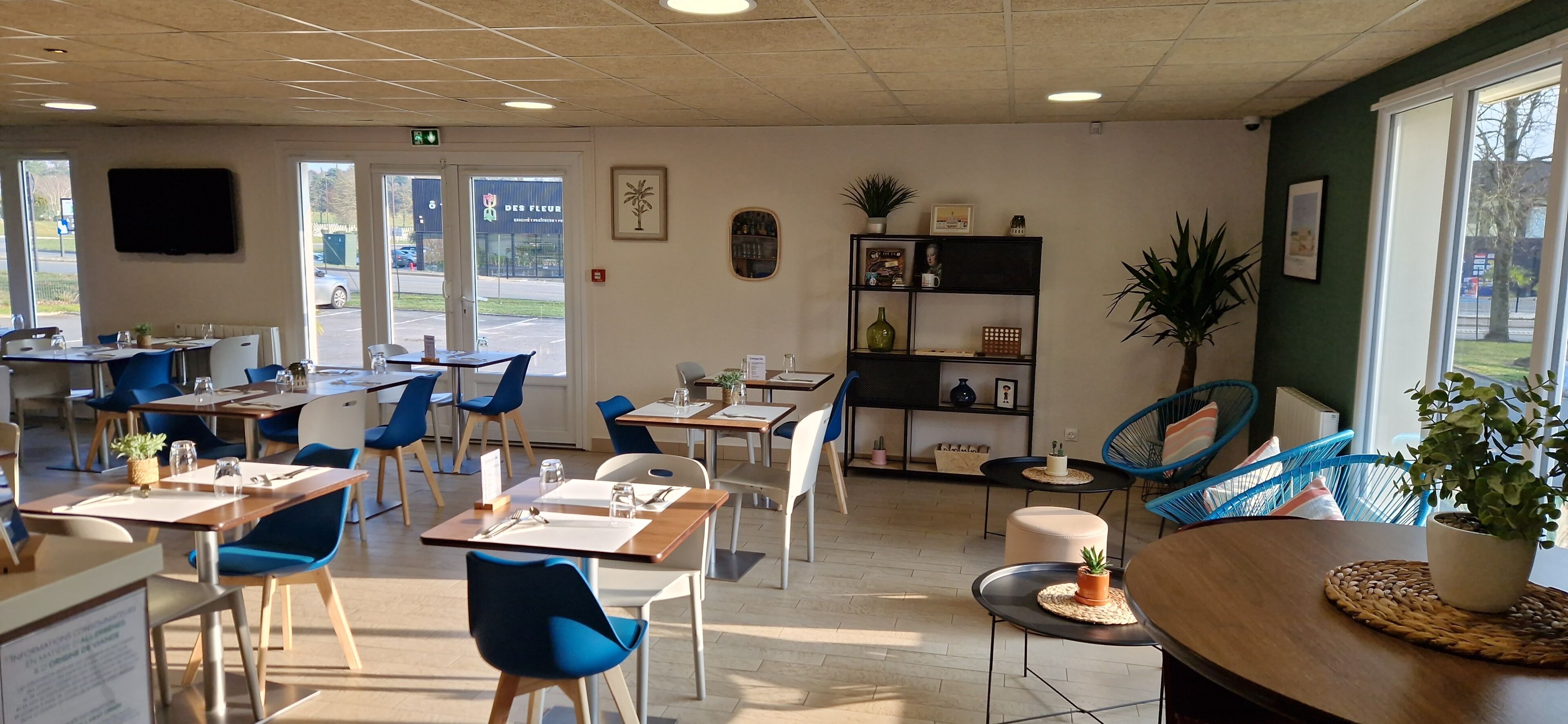 Un restaurante con mesas, sillas, una estantería y un televisor en la pared.
