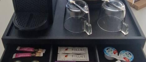 Uma estação de café com cafeteira, xícaras e sachês de chá Lipton.