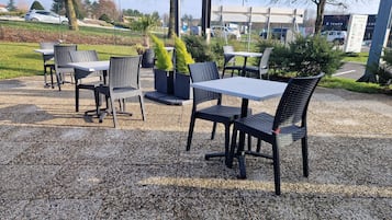Un área con mesas y sillas al aire libre, rodeada de grava y vegetación.