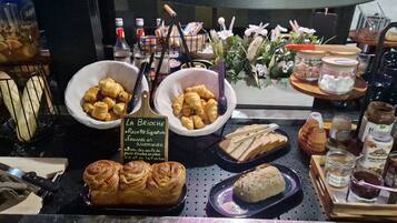 A bakery display with various baked goods and pastries, including croissants and bread, along with jars of spreads and condiments.