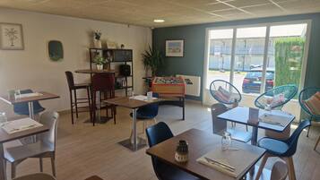 A cozy indoor space with tables and chairs, a foosball table, and a view of the outside.