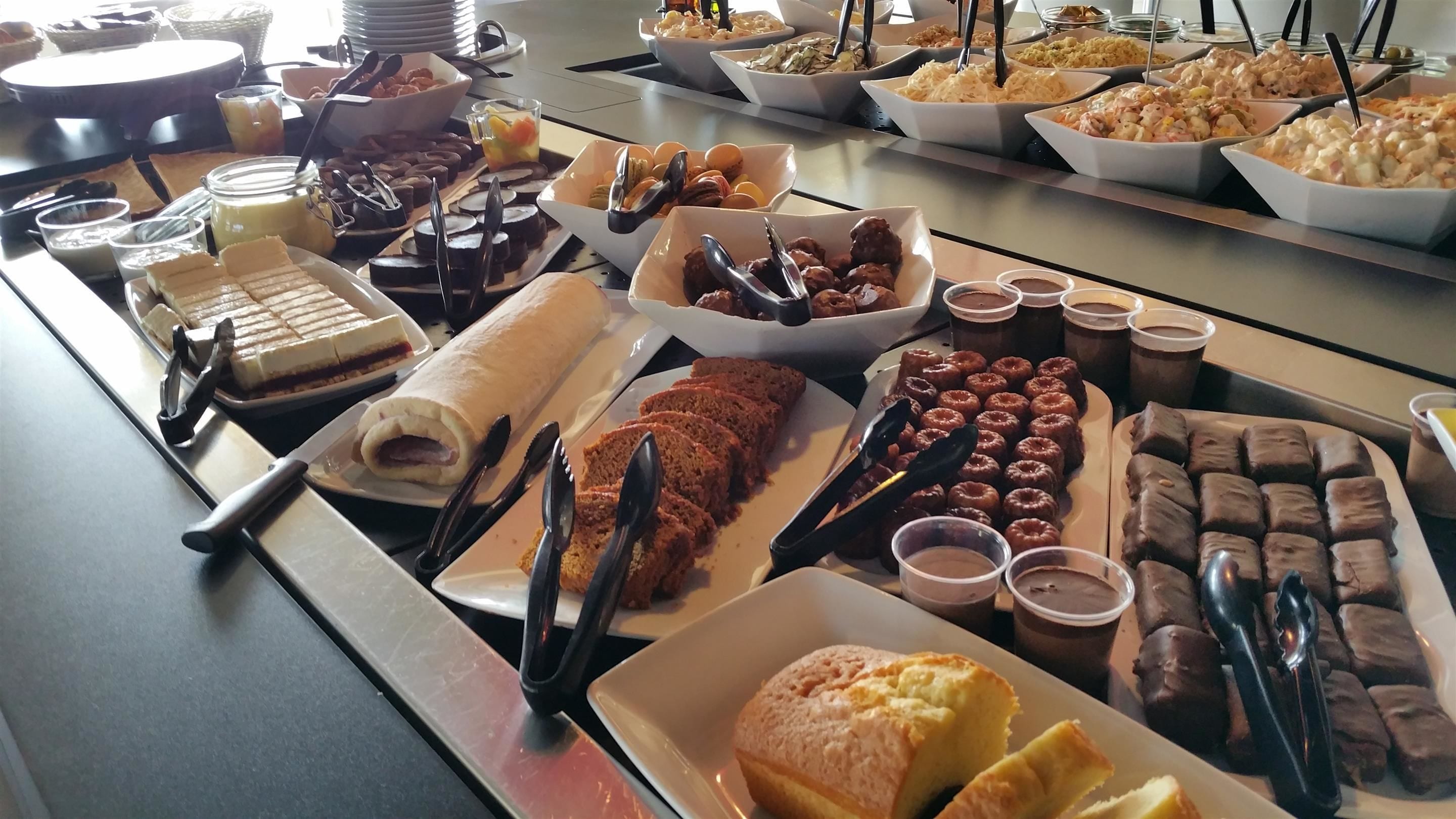 Un buffet proposant une variété de plats, notamment des pâtisseries, des desserts et des boissons.