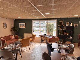 Una habitación acogedora con mesa de futbolín, sofá y comedor con mesas y sillas.