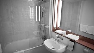 A modern bathroom with a glass-enclosed shower, a white sink, and a wooden vanity.
