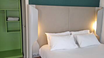 Een net opgemaakt bed met witte lakens en een hoofdbord met een turquoise accent.