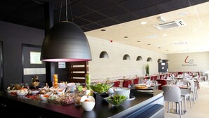 A buffet setup with various food items and a restaurant sign in the background.