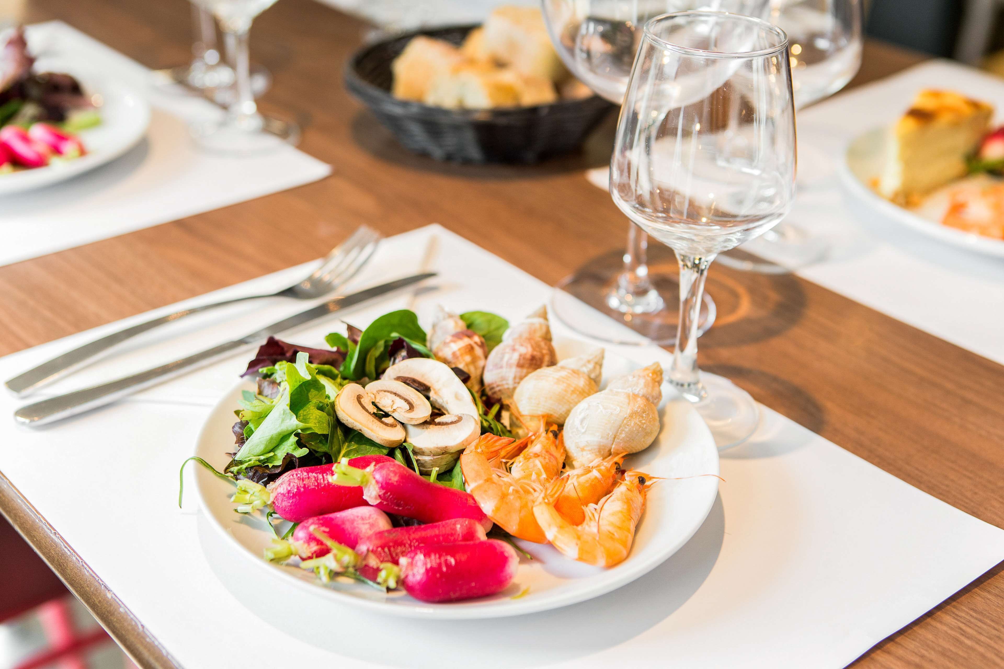 Una mesa de comedor con un plato de comida, una copa de vino y cubiertos.
