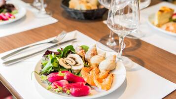 A dining table with a plate of food, a wine glass, and cutlery.