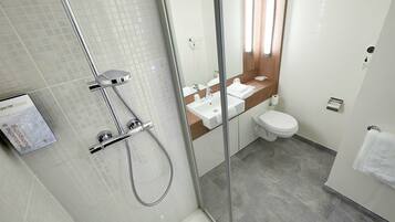 Une salle de bain moderne dotée d’une douche à parois de verre, d’un lavabo et de toilettes.